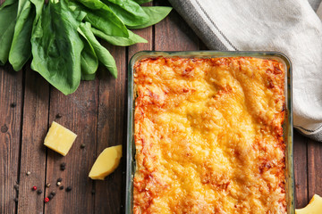 Delicious lasagna with spinach and cheese on wooden background