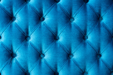 Coach-type velours screed tightened with buttons. Blue chesterfield style quilted upholstery backdrop close up. texture background