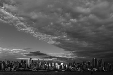 Wall Mural - JUNE 6, 2018 - NEW YORK, NEW YORK, USA  - New York City and Hudson River at sunset black and white with ominous clouds over the Manhattan Skyline in black and white