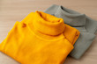 Warm clothes in the form of turtlenecks. Yellow and gray knitted turtlenecks for cold seasons. Women's fashion clothing for autumn and winter.