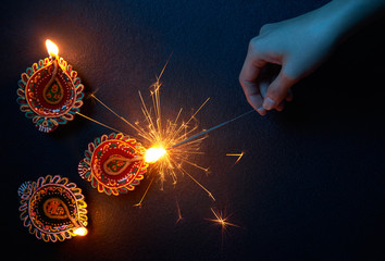 Wall Mural - Lighting a sparkler with diya lamp