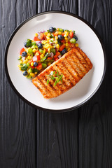 Wall Mural - Freshly cooked grilled salmon filet with pepper, corn, blueberry and onion salad close-up. Vertical top view