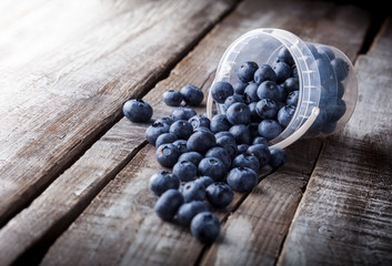 Wall Mural - Blueberries arrangement in plastic can spilled on white wooden table in studio