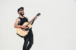 © 4Max - Guitar player singing outside. Hipster guitar player with beard and black clothes