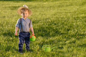 Wall Mural - Toddler child outdoors. One year old baby boy wearing straw hat using watering can