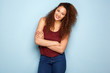 © mimagephotos - trendy young woman with curly hair smiling by blue background