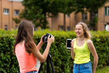 Two girls are teenagers. Summer in nature. Writes the video to the camera. In hands holds the phone. Concept review smartphone. Smiles happily.