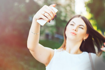  young beautiful woman, teenager, making selfie in park, girl is unfocused, focus on smartphone
