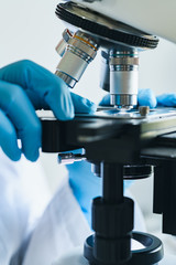 Wall Mural - scientist hands with microscope close-up shot in the laboratory