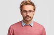 © wayhome.studio - Serious male teacher with confident clever look, has beard and mustache, listens pupil`s answer, wears pink sweater, round glasses, isolated over white background. People, facial expressions concept