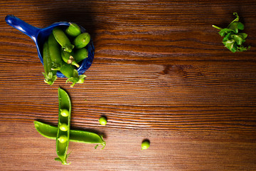 Wall Mural - Fresh, young green peas in blue bowl on the old wooden background. Bio healthy food. Selective focus. Copy space background