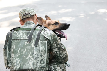 Man in military uniform with German shepherd dog outdoors