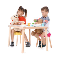 Little children playing tea party with toys on white background. Indoor entertainment