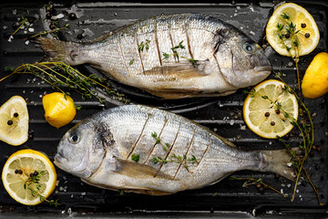 Fresh Dorada fish, sea bream with the addition of spices, herbs and lemon prepared for grilling on the grill barbecue, top view