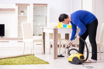 Young man vacuum cleaning his apartment