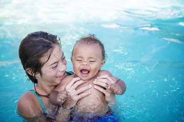 Two cute kids playing in a swimming pool on a sunny day while on vacation. Bright colorful fun summer photo with copy space