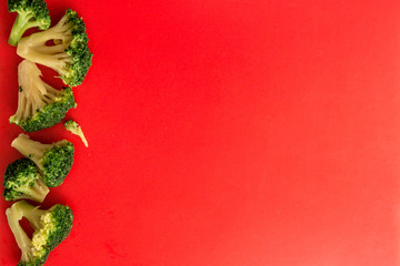 copy space with fresh broccoli pieces on one edge of a bright red background