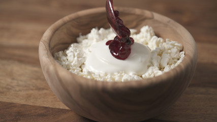 Sticker - closeup adding cowberry jam to cottage cheese in wood bowl