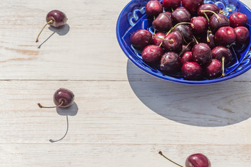 blue plate of ripe sweet cherry on white wooden table