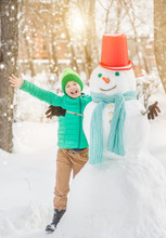 Joyful Boy With Snowman At Sunset