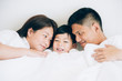 © ic36006 - Happy aian family lying in bed and sleeping.