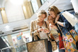 © goodluz - Girls in shopping mall using smartphone