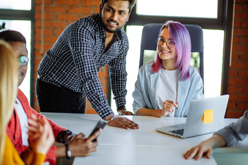 Wall Mural - Close up of multiethnic creative group of people sitting at the white table, discussing startup of new trendy project. Corporate Concept