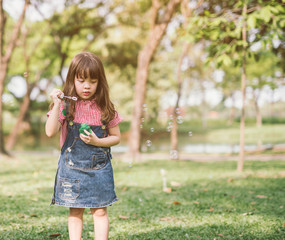 Wall Mural - A little girl blowing soap bubbles in summer park