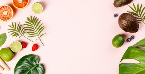 Tropical fruits and leaves on pink pastel background