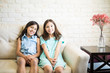 © AntonioDiaz - Elder and younger sisters posing together on the couch at the camera