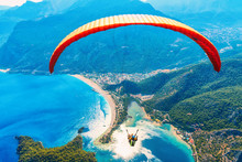 Paragliding In The Sky. Paraglider Tandem Flying Over The Sea With Blue Water And Mountains In Bright Sunny Day. Aerial View Of Paraglider And Blue Lagoon In Oludeniz, Turkey. Extreme Sport. Landscape