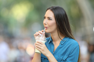 Wall Mural - Woman drinking a smoothie looking at side