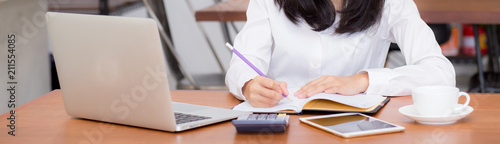 Fotomural Closeup banner asian woman writing on notebook on table with laptop, girl work at coffee shop, freelance business concept