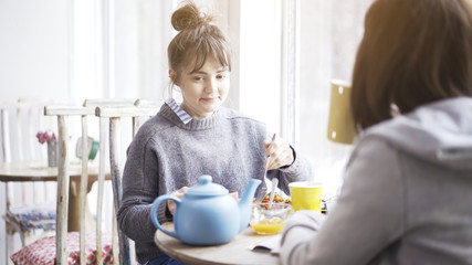 A young cute shy woman eating salad in a cafe feeling ashamed or surprised sitting in front of her female friend