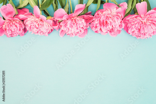 Beautiful background with border of pink peony flowers on blue. Top view, pla...
