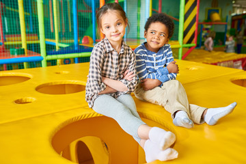 Wall Mural - full length portrait of cute girl and african-american boy posing sitting on top of cheese like box 