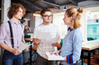 © pressmaster - Two young businessmen with papers talking to their colleague with notebook about working moments