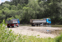 Crossing A Trucks Through A Shallow Mountain River. Transportation Of Goods In Hard-to-reach Places And Dangerous Conditions. Ecology Of The Environment. Rest Over The Water. The River Is A Region