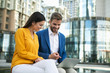 © Yakobchuk Olena - Excited businessman showing presentation on laptop to his colleague. Woman is looking at gadget with interest and smiling with satisfaction. They are sitting outdoor in city