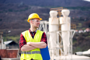 Wall Mural - Male engineer wearing reflective vest and hardhat standing with clipboard