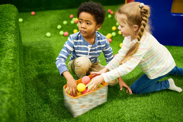 Wall Mural - portrait of two cute little children playing in children room, focus on african-american boy looking