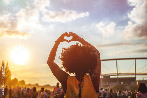 Cuadros en Lienzo Young African American woman at summer holi festival make heart symbol by hands,