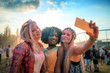 © leszekglasner - Multiethnic girls covered in colorful powder taking selfie at summer holi festival
