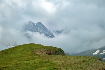 Poster - mountain plateau covered with green grass and a mountain peak surrounded by dense clouds landscape background screensaver on the screen