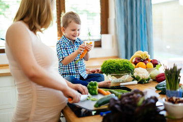 Pregnant woman preparing meal with son