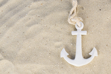 A white anchor in the sand on the beach