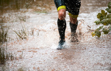 Cross Country Trail Runner Moving Through Water On Rural Road
