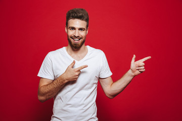 Wall Mural - Handsome happy young man in white t-shirt pointing.