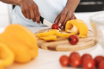 Wall Mural - Close up of a afro american woman chopping vegetables