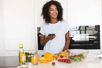 Wall Mural - Portrait of a smiling afro american woman using mobile phone